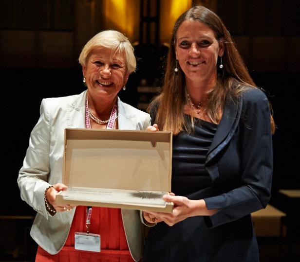 Zwei Frauen halten eine offene Schachtel mit einem Preis darin.