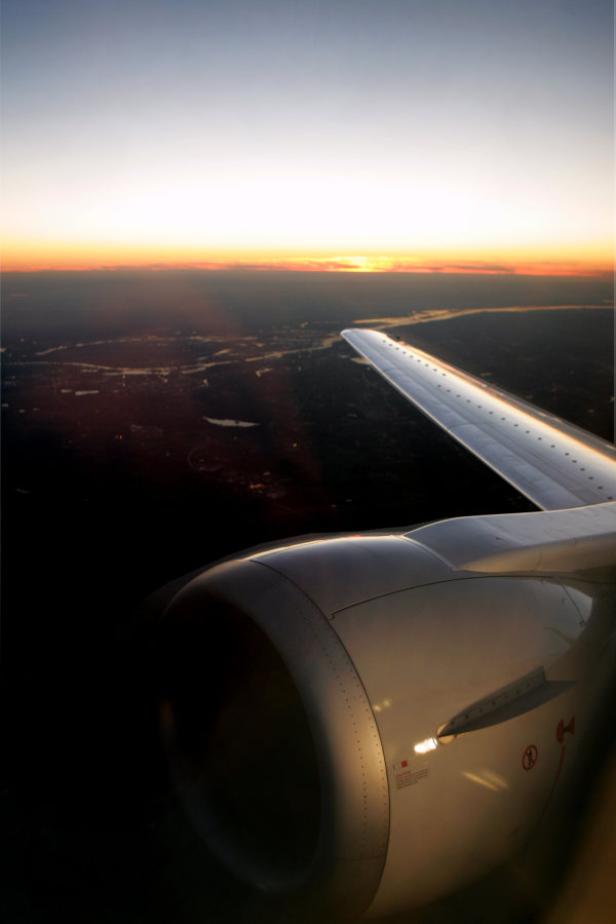 Blick aus einem Flugzeugfenster auf den Sonnenuntergang.