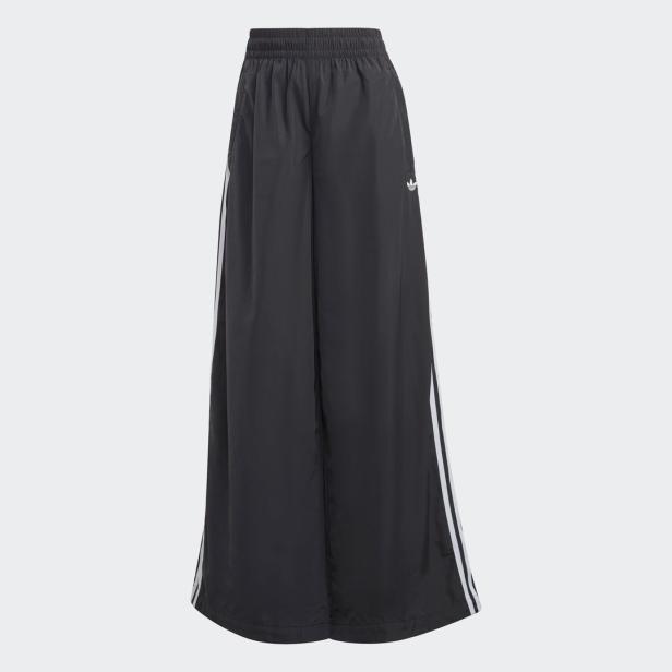 Eine schwarze Adidas-Hose mit weitem Bein und weißen Streifen an der Seite.