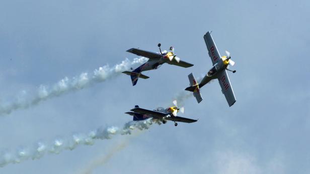 Drei Red Bull Flugzeuge fliegen in Formation am Himmel.