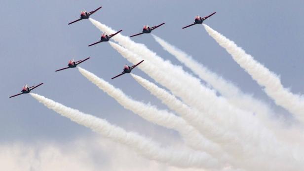 Sieben Flugzeuge ziehen Rauchstreifen in den Himmel.
