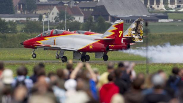 Ein rot-silbernes Flugzeug landet vor einer Zuschauermenge.