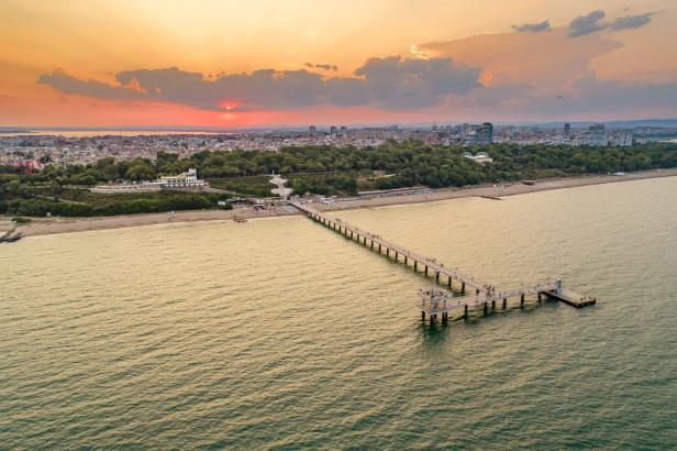 Blick auf die Küstenlinie von Burgas, Bulgarien, mit einer Seebrücke im goldenen Abendlicht.
