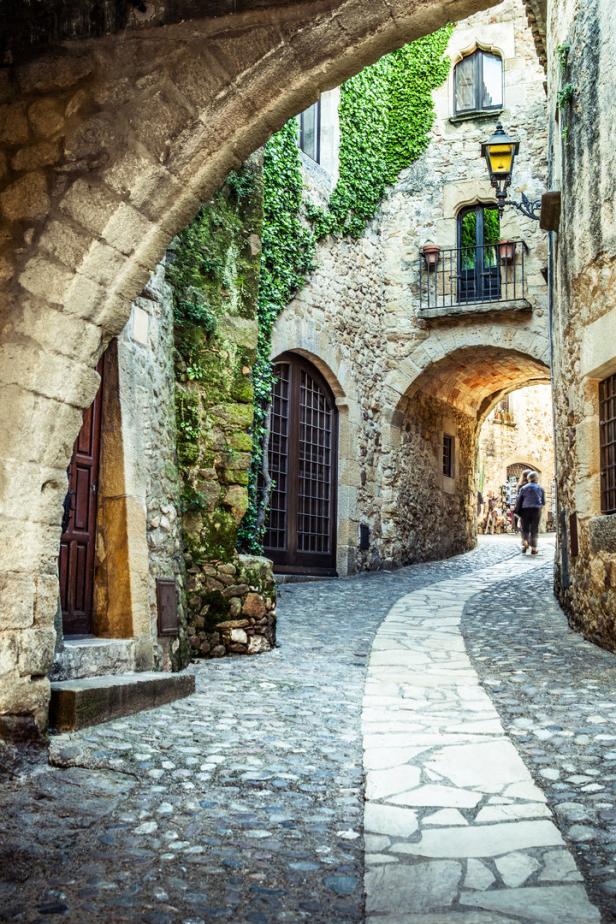 Eine Gasse in einem alten Dorf mit Steinmauern und Kopfsteinpflaster.