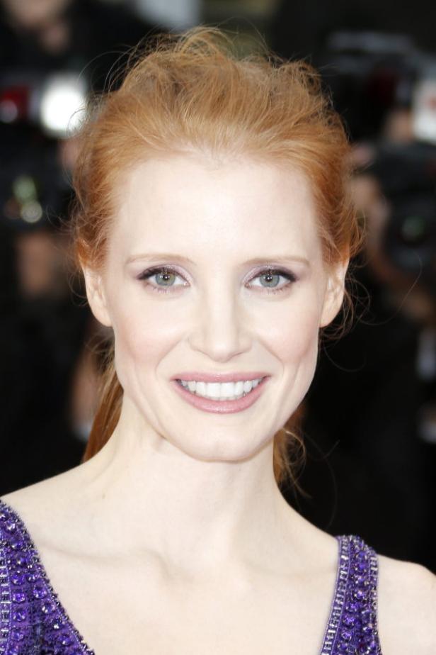 Porträt von Jessica Chastain mit hochgesteckten roten Haaren und einem lila Kleid.