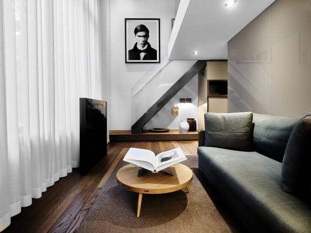 Ein Wohnzimmer mit einem grauen Sofa, einem runden Tisch und einer Treppe.
