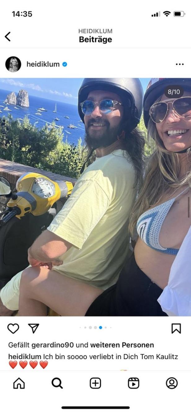 Heidi Klum und Tom Kaulitz auf einem gelben Motorroller vor einer Küstenlandschaft.
