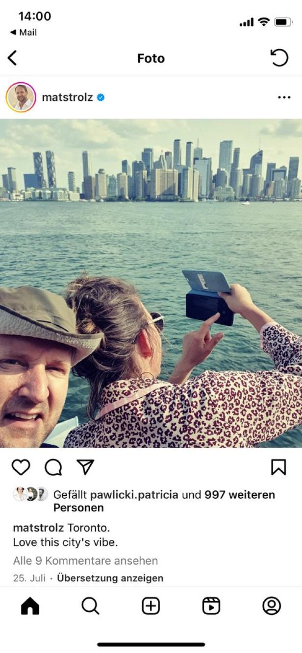 Ein Mann mit Hut und eine Frau machen ein Foto von der Skyline von Toronto vom Wasser aus.