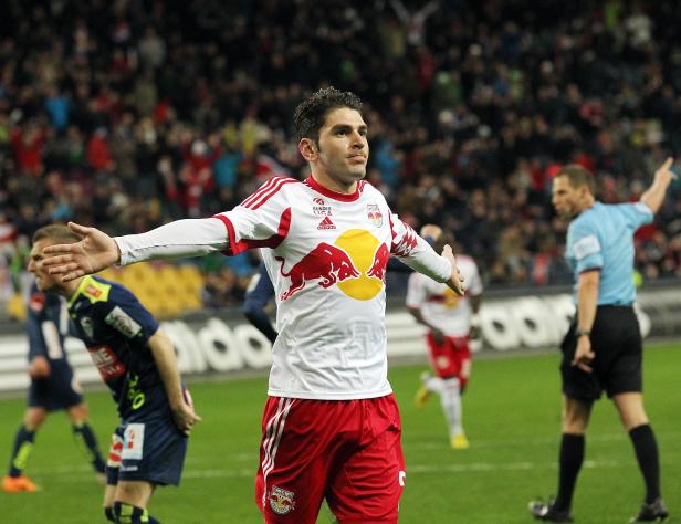 Ein Fußballspieler von Red Bull Salzburg jubelt mit ausgestreckten Armen auf dem Spielfeld.