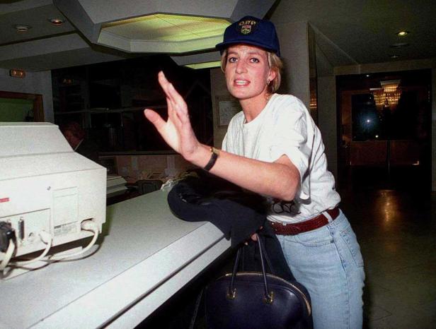 Prinzessin Diana winkt in einem lässigen Outfit in einem Innenraum.