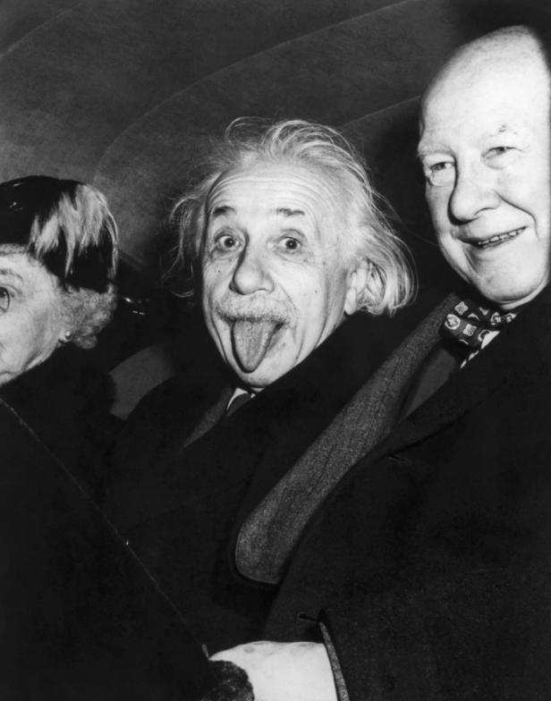Albert Einstein streckt in einem Auto sitzend die Zunge heraus.