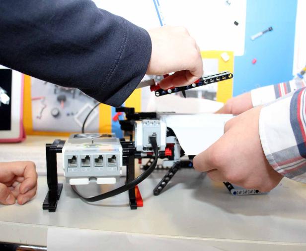 Zwei Personen arbeiten an einem Robotermodell aus Legosteinen.