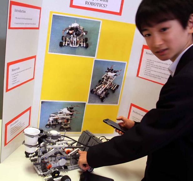 Ein Junge präsentiert sein Robotik-Projekt mit einem Roboter aus Legosteinen.