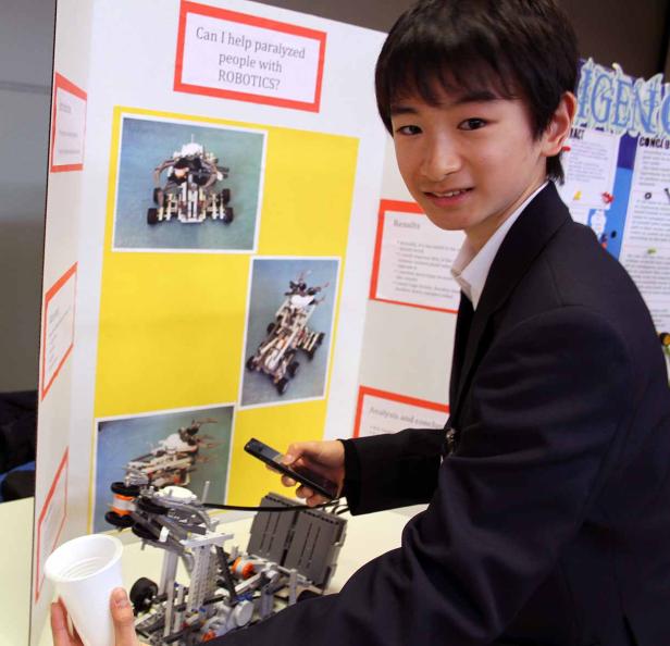 Ein junger Mann präsentiert ein Robotik-Projekt zur Unterstützung von Menschen mit Lähmungen.