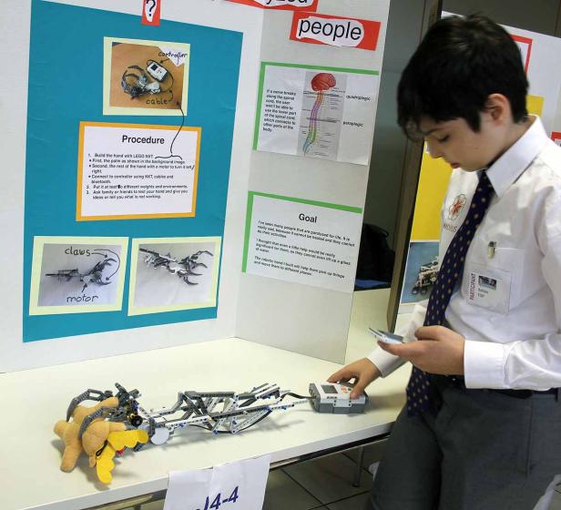 Ein Schüler präsentiert eine Roboterhand aus Lego, die entwickelt wurde, um Menschen mit Lähmungen zu helfen.