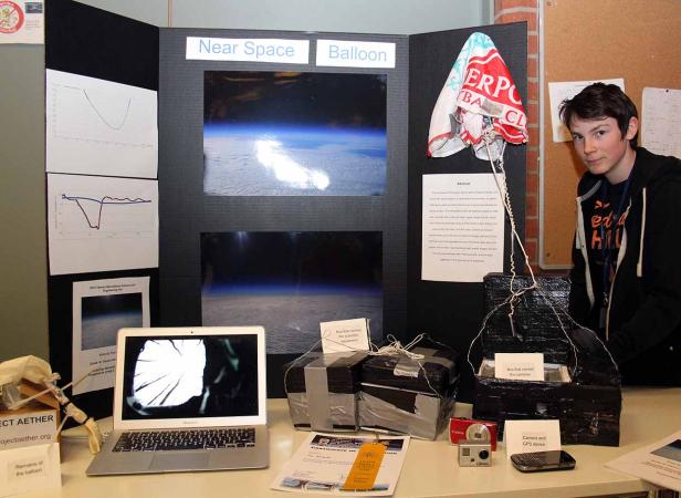 Ein Schüler präsentiert ein Projekt zum Thema Near-Space-Ballon mit Fotos und Experimentierausrüstung.