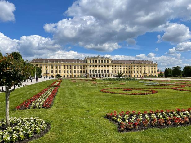 Das Schloss Schönbrunn mit seinem weitläufigen Garten unter einem bewölkten Himmel.