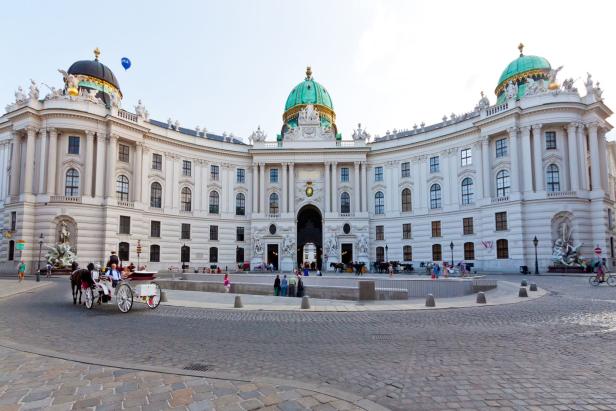 Die Hofburg in Wien mit einer Pferdekutsche im Vordergrund.