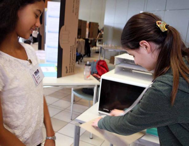 Zwei junge Frauen arbeiten an einem Projekt in einem hellen Raum.