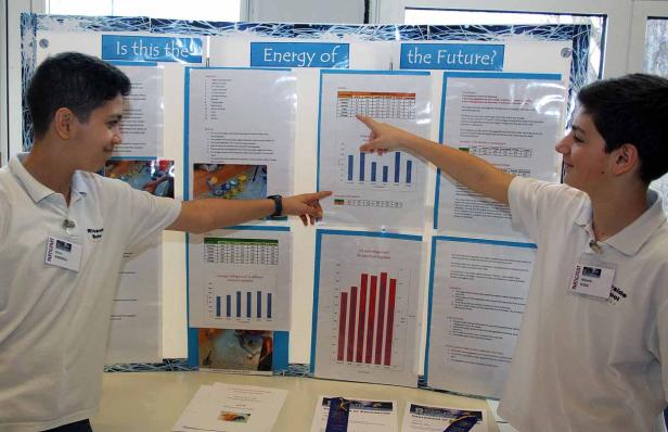 Zwei Jugendliche präsentieren ein Wissenschaftsprojekt über Energie aus Obst und Gemüse.