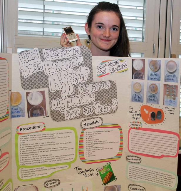 Ein junges Mädchen präsentiert ein Wissenschaftsprojekt über die Auswirkungen elektronischer Verschmutzung auf Hefe.
