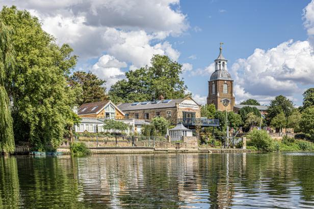 Blick über das Wasser auf Gebäude und einen Kirchturm in Henley-on-Thames.