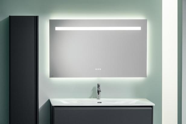 Ein Badezimmer mit einem beleuchteten Spiegel über einem Waschbecken.