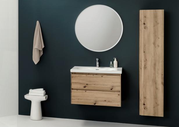 Ein Badezimmer mit einem Waschtisch aus Holz, einem runden Spiegel und einem Handtuchhalter.
