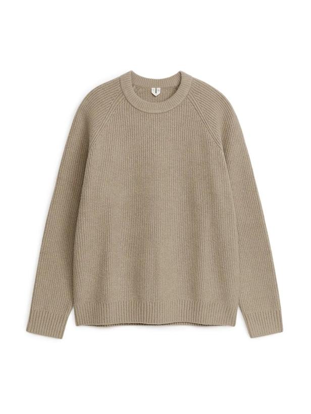 Ein beiger Strickpullover mit Rundhalsausschnitt liegt vor einem weißen Hintergrund.