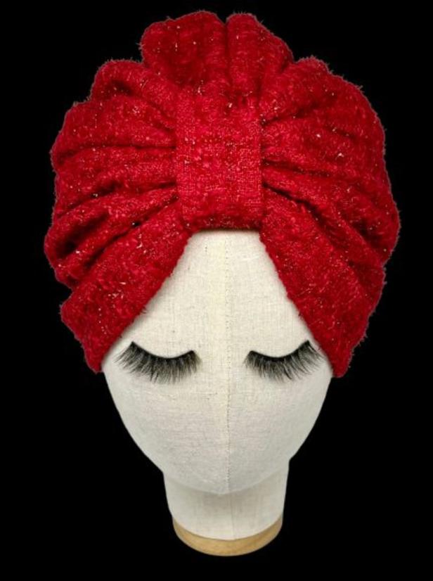 Ein roter Turban mit Schleife auf einem Schaufensterpuppenkopf mit langen Wimpern.