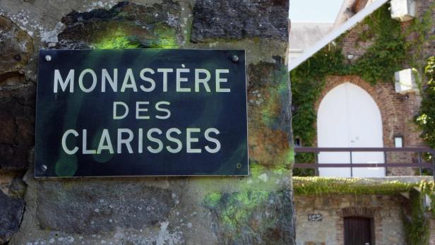 Ein Schild mit der Aufschrift „Monastère des Clarisses“ vor einem Gebäude.
