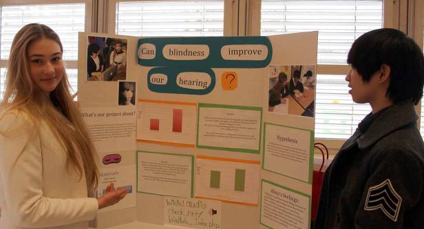 Zwei Schüler präsentieren ein Projekt über den Zusammenhang von Blindheit und Hörvermögen.