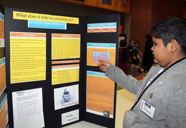 Ein Schüler präsentiert sein Projekt über menschliche Psychologie auf einer Wissenschaftsmesse.