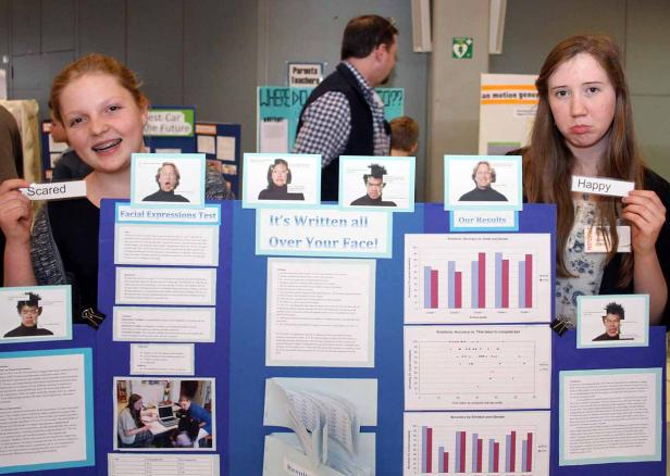 Zwei Mädchen präsentieren ein Wissenschaftsprojekt über Gesichtsausdrücke.