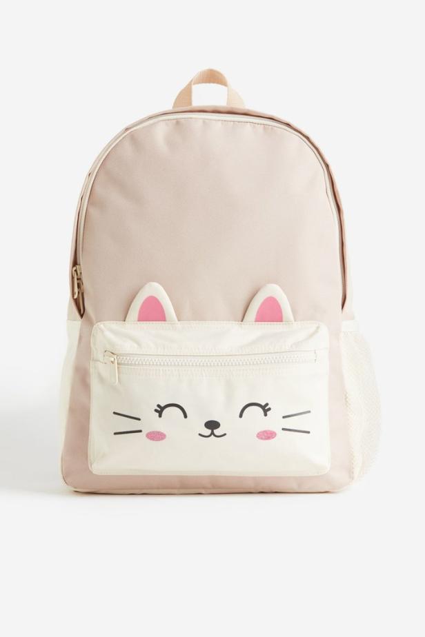 Ein rosafarbener Rucksack mit einem aufgedruckten Katzengesicht auf der Vordertasche.