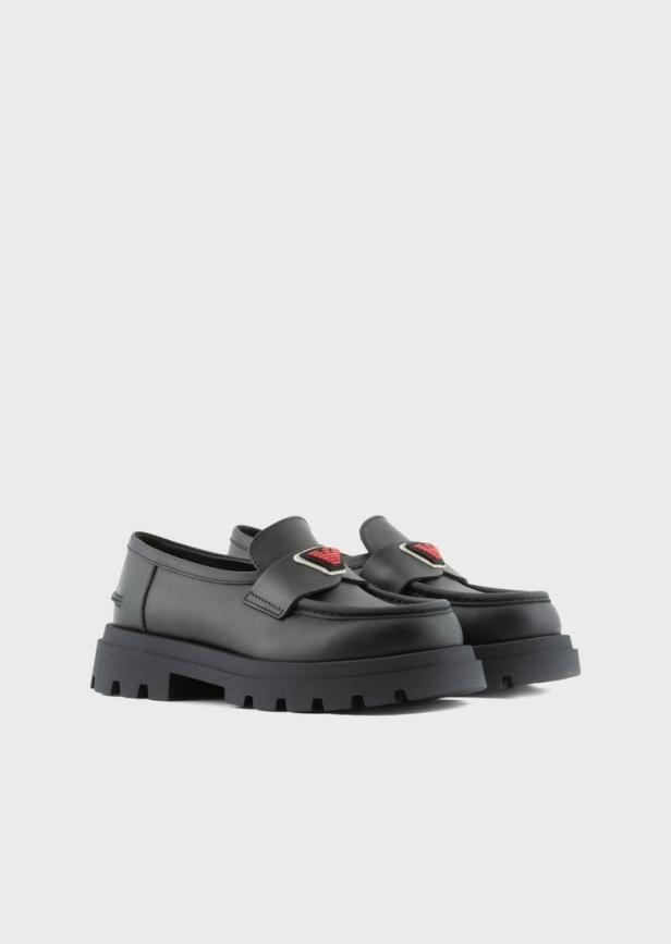 Ein Paar schwarze Loafer mit rotem Logo auf einer dicken Plateausohle.