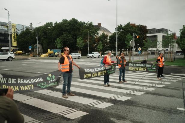 Klimaaktivisten stehen auf einem Zebrastreifen und blockieren den Verkehr in St. Pölten