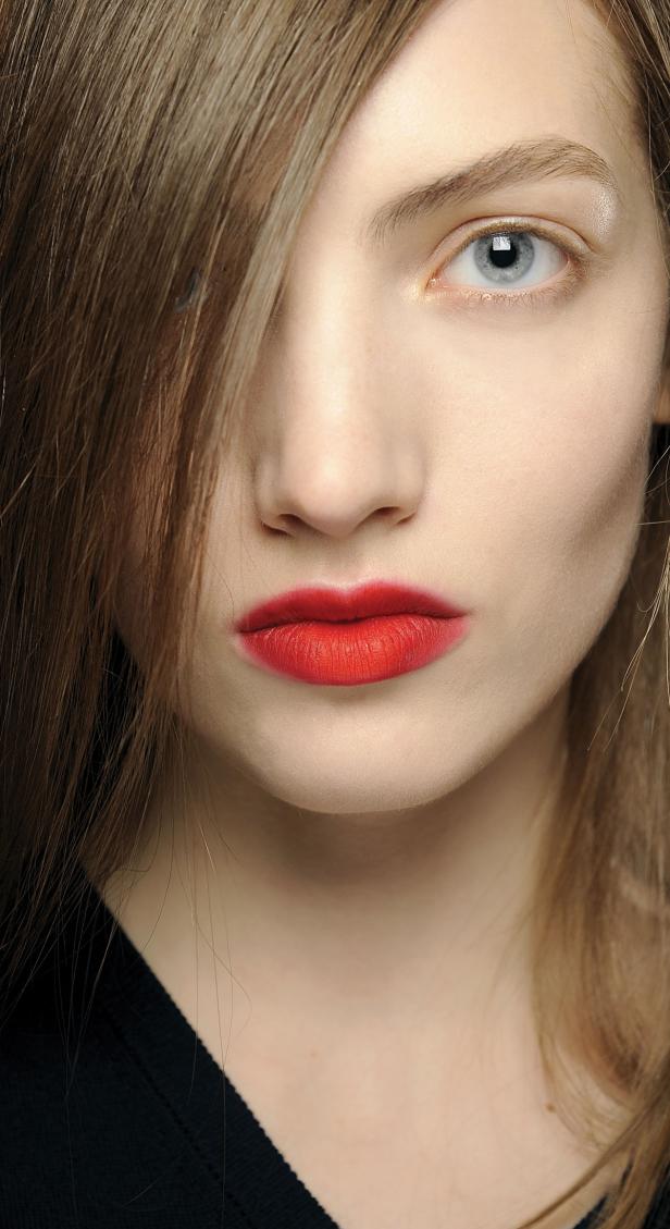 Nahaufnahme des Gesichts einer Frau mit roten Lippen und blonden Haaren, die ihr Auge bedecken.