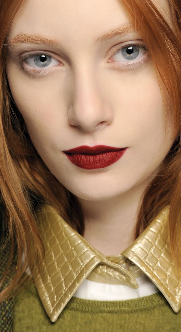 Porträt einer Frau mit roten Lippen und hellblauen Augen.