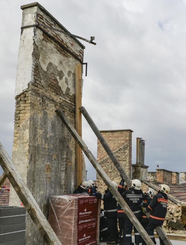 Feuerwehrleute sichern einen beschädigten Schornstein mit Holzstützen.