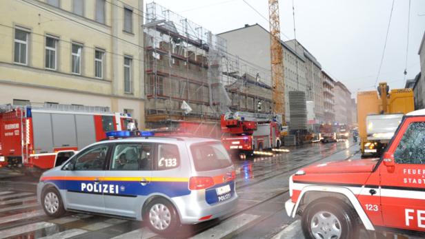 Auf einer regnerischen Straße stehen Einsatzfahrzeuge von Polizei und Feuerwehr.