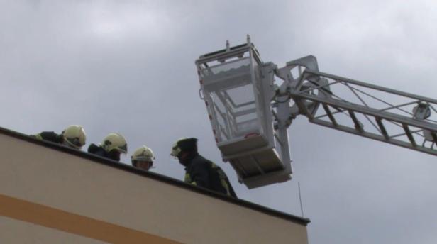 Feuerwehrleute stehen auf einem Dach neben einer Drehleiter.