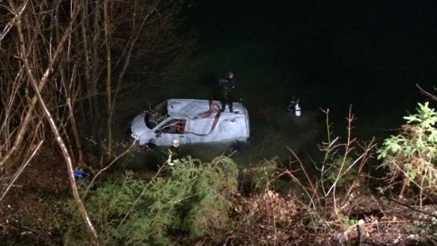 Ein Lieferwagen steht teilweise im Wasser, während Rettungskräfte und Taucher vor Ort sind.
