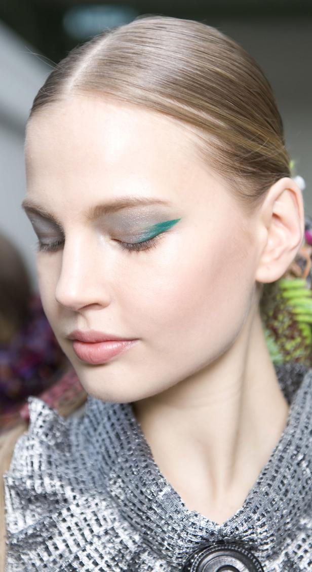 Nahaufnahme einer Frau mit silbernem Lidschatten und grünem Eyeliner.