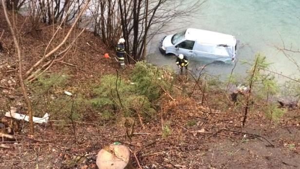 Ein Lieferwagen ist in einen See gefahren, während zwei Feuerwehrleute in der Nähe stehen.