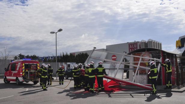 Feuerwehrleute begutachten einen umgestürzten Unterstand vor einem McDonald's Restaurant.