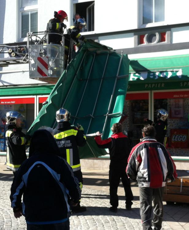 Feuerwehrleute entfernen eine Markise vor einem Geschäft in Chemnitz-Stadt.