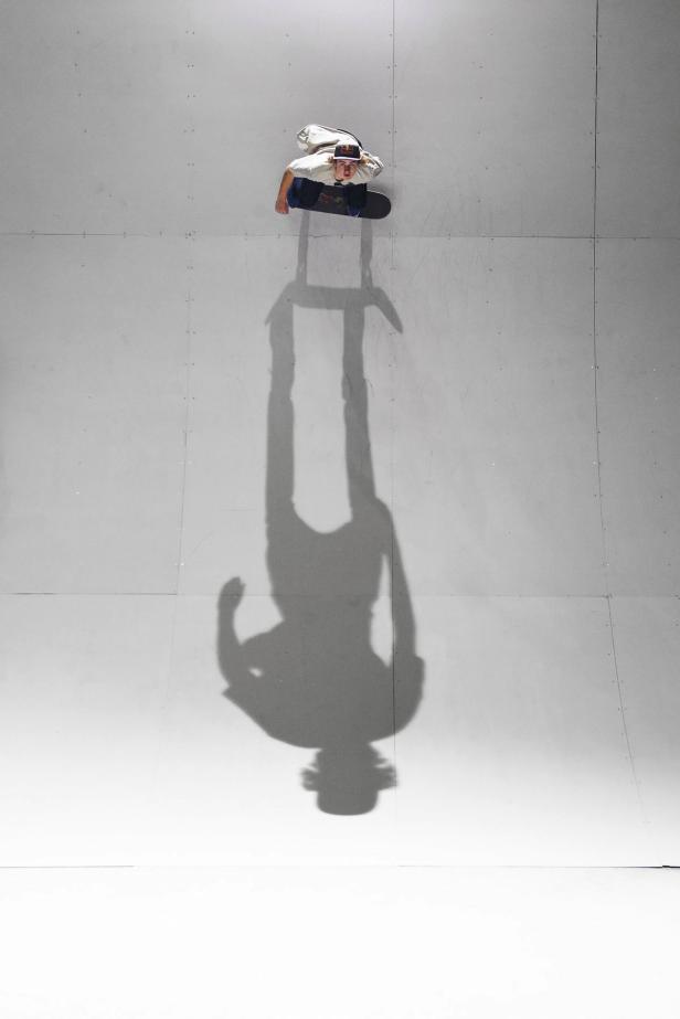 Ein Skateboarder steht auf einer Rampe, sein langer Schatten fällt auf den Boden.