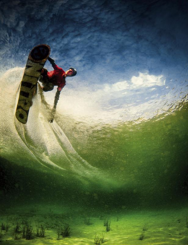 Ein Wakeboarder springt über eine Welle, Unterwasseraufnahme.