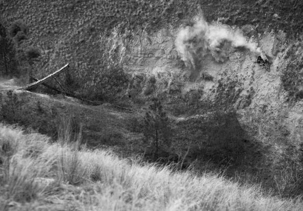 Ein Mountainbiker fährt einen steilen Hang hinunter und wirbelt Staub auf.